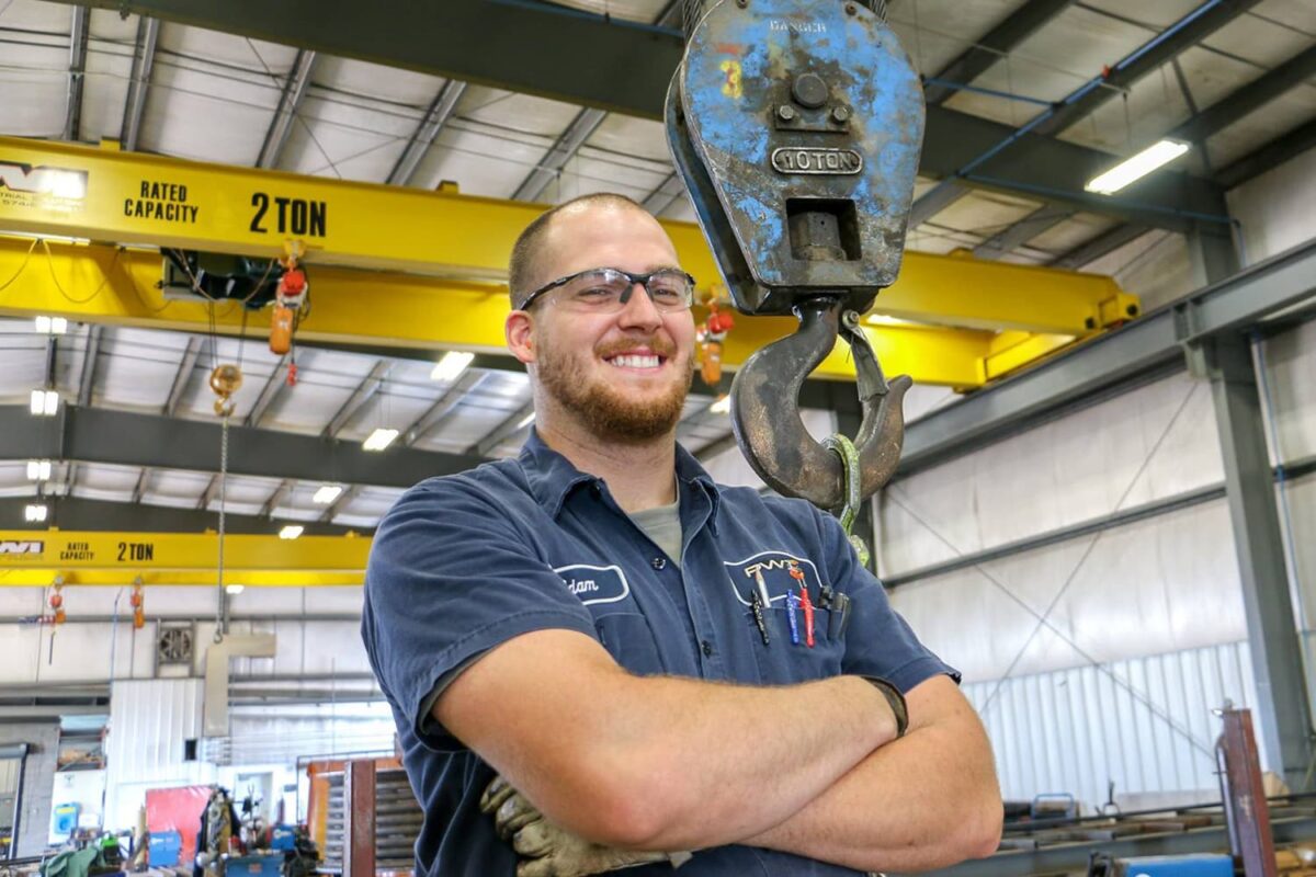 Factory Worker with Overhead Crane in Background